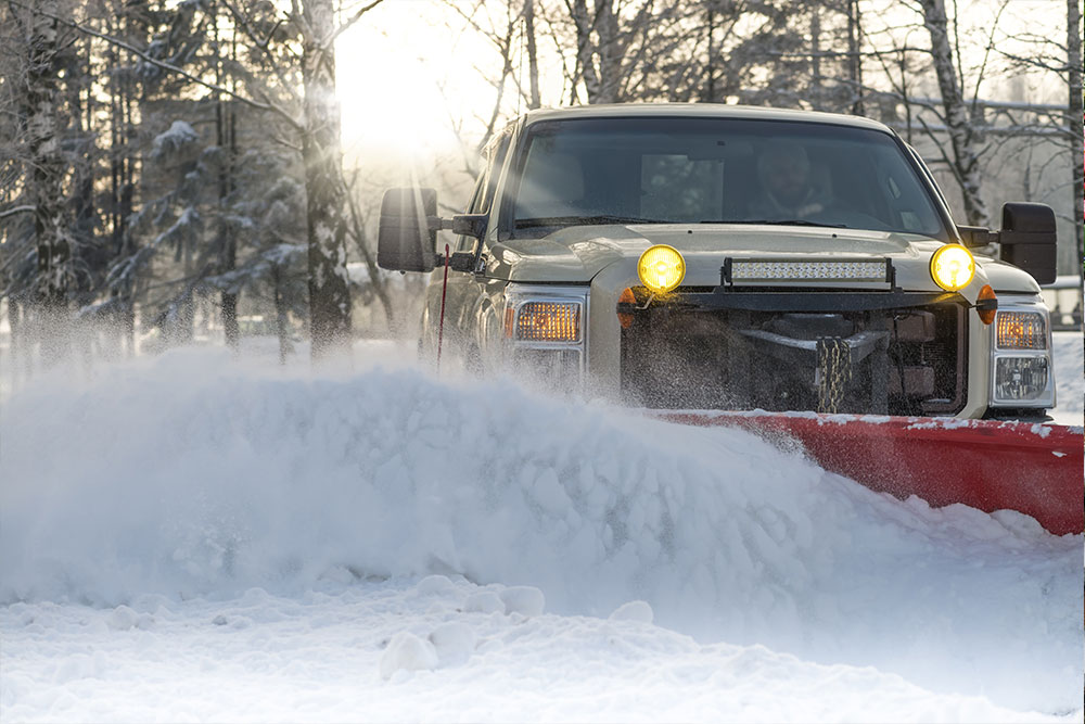 Professional snow plow truck clearing parking lot